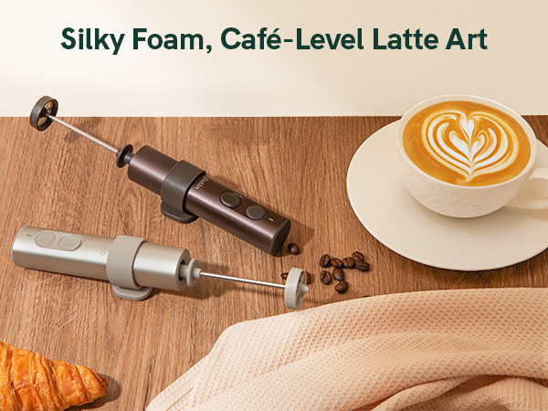 Text reads "Silky Foam, Café-Level Latte Art". Two metallic milk frothers displayed on wooden surface with latte coffee cup showing decorative latte art foam design.