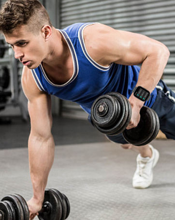 Man in blue tank top performing push-up with dumbbell. Focused on arm muscles and exercise form in gym setting.