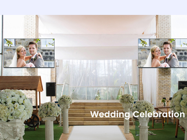 Indoor wedding venue setup with white sheer curtains, wooden chairs, and floral decorations in white and green.