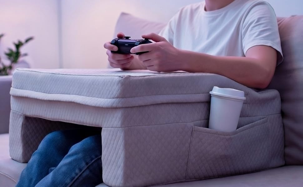 Man playing a game console while resting a gaming pillow on his lap on a couch