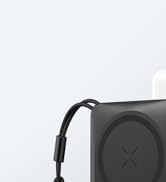 Close-up of a black electronic device with a curved cable attached. The device has a circular pattern and an X-shaped marking on its surface.