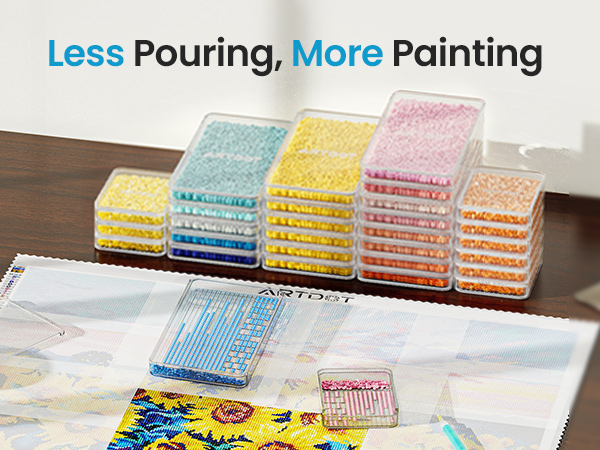 Paint organization system with stackable transparent containers filled with colorful paint beads. Containers sit on wooden surface near an in-progress watercolor painting.