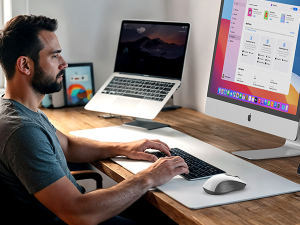 Work setup showing dual monitor desktop configuration with laptop and peripheral devices on wooden desk.