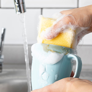 Person using Dawn Ultra to clean a coffee mug.