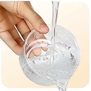 Hand holding a transparent, flexible object being dipped into a clear liquid in a glass container, demonstrating its properties.