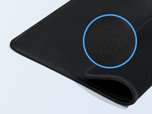 Close-up of a black textured gaming mousepad corner, showing detailed mesh fabric surface with blue circular highlight indicator.