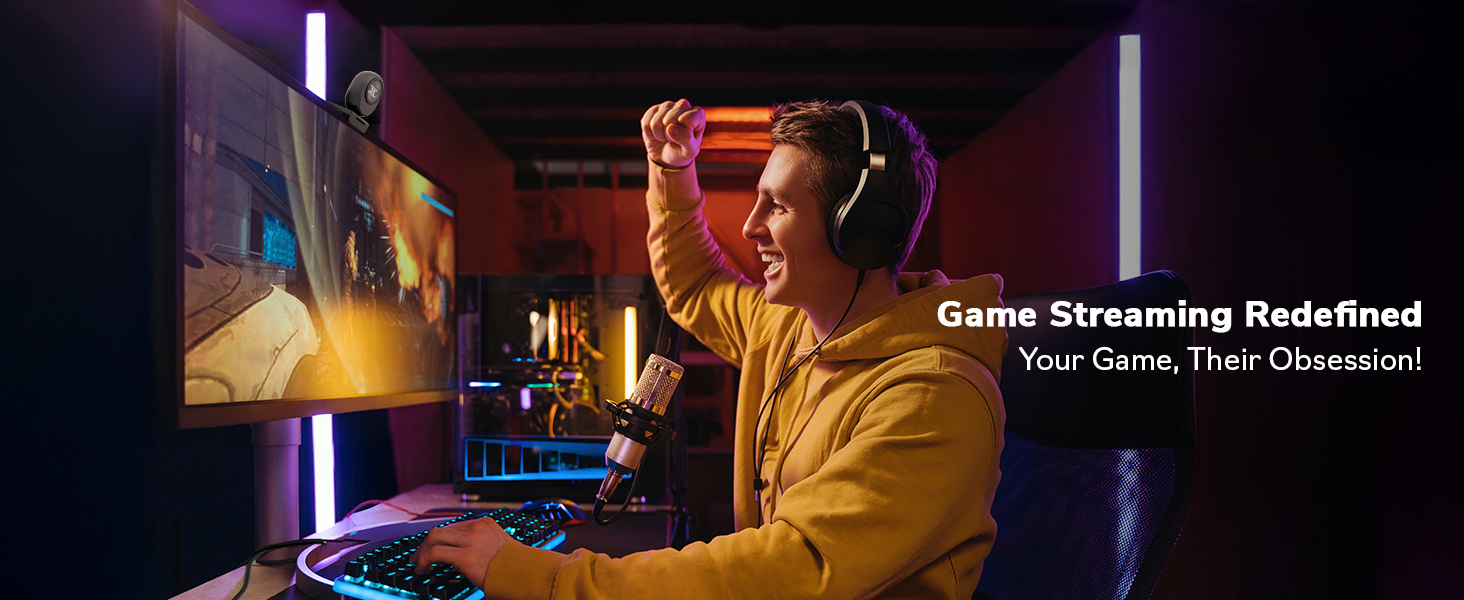 Gamer in yellow hoodie using keyboard and controller, playing on large screen in dimly lit room. Text overlay reads 'Game Streaming Redefined: Your Game, Their Obsession!'