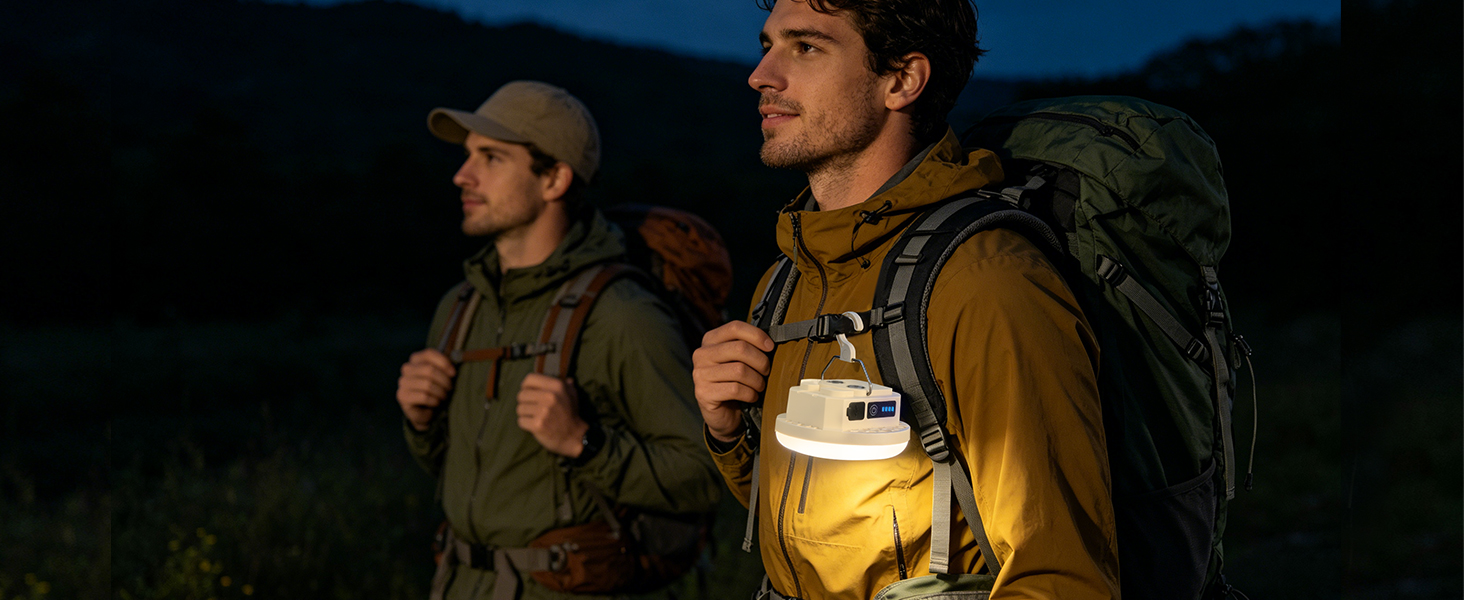 Two hikers walking at night with a portable LED camping lantern clipped to a backpack