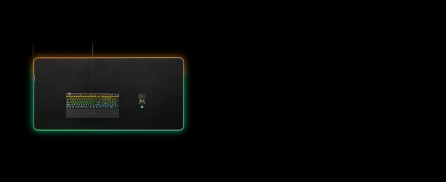 -SteelSeries QcK Prism 3XL mousepad with an Apex keyboard laying flat on a dark surface