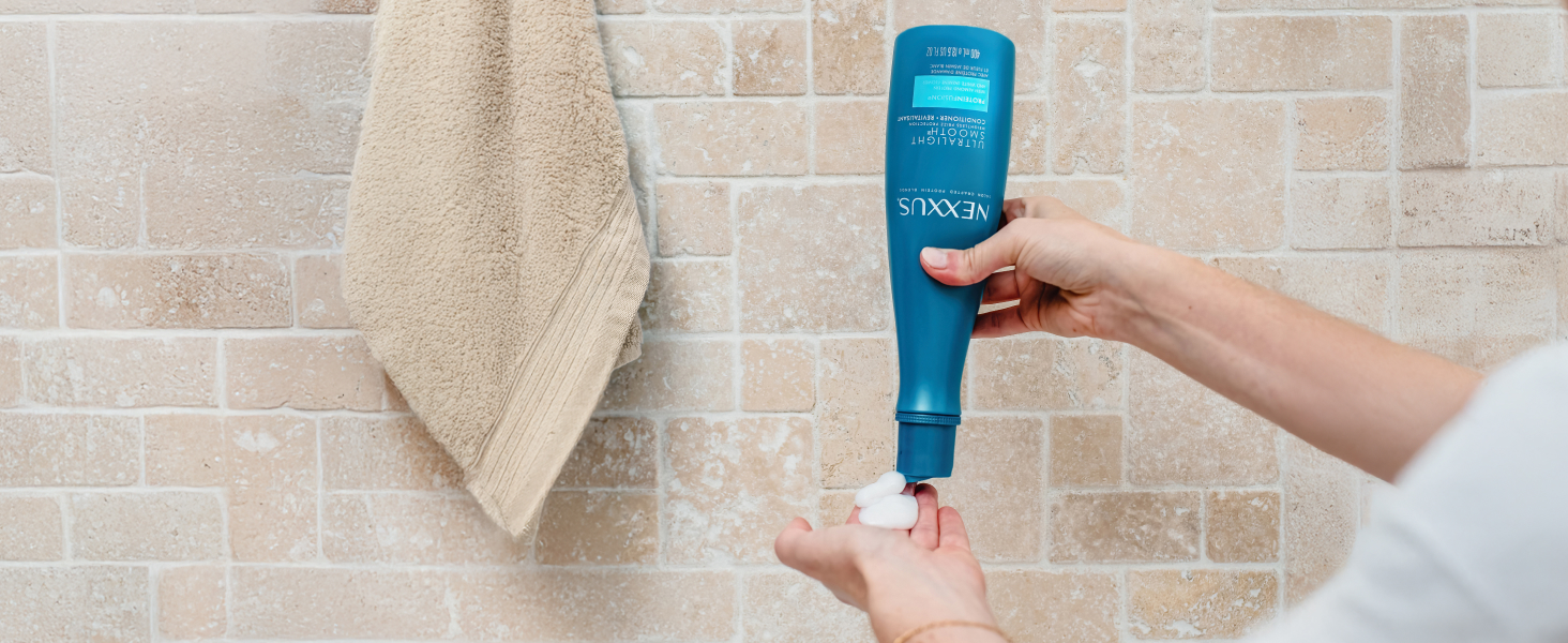Hand holding actual liquid product and another hand holding its bottle in a bathroom.