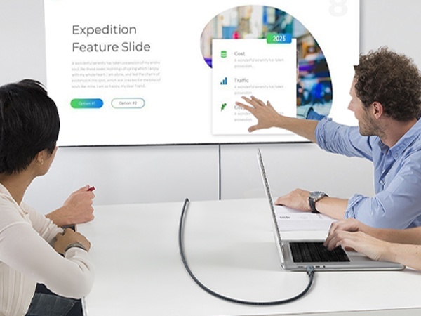 Office meeting scene showing interactive presentation on wall-mounted display with people collaborating in modern workspace.