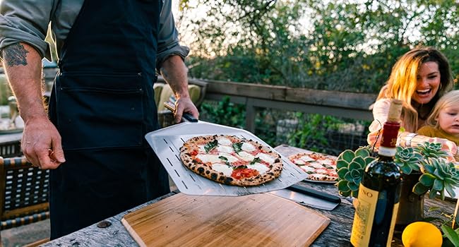 a man holding a pizza on a wooden table