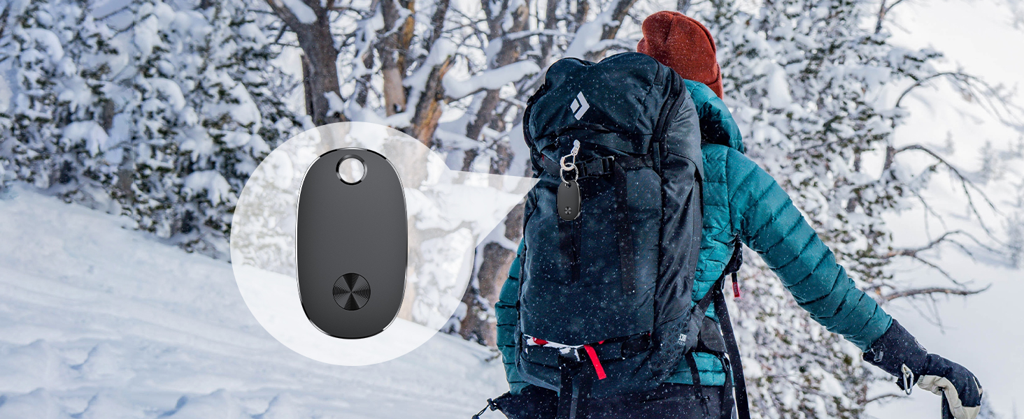 Small, oval-shaped black device with four-leaf clover icon, inset next to person wearing winter gear and backpack in snowy forest setting.