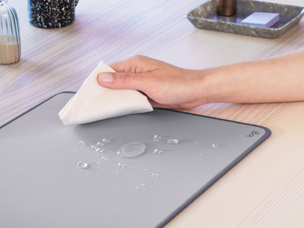 A zoom of a hand cleaning the Desk Mat