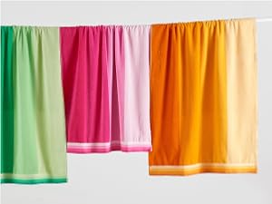 beach towels with an alternate gradient stripe design, hanging from a clothing line