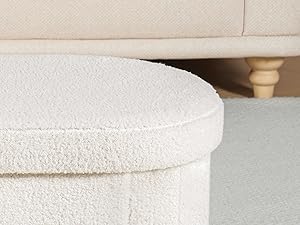 Close-up of a cream-colored textured fabric surface, possibly upholstery or a cushion. Soft, plush appearance with visible texture details.