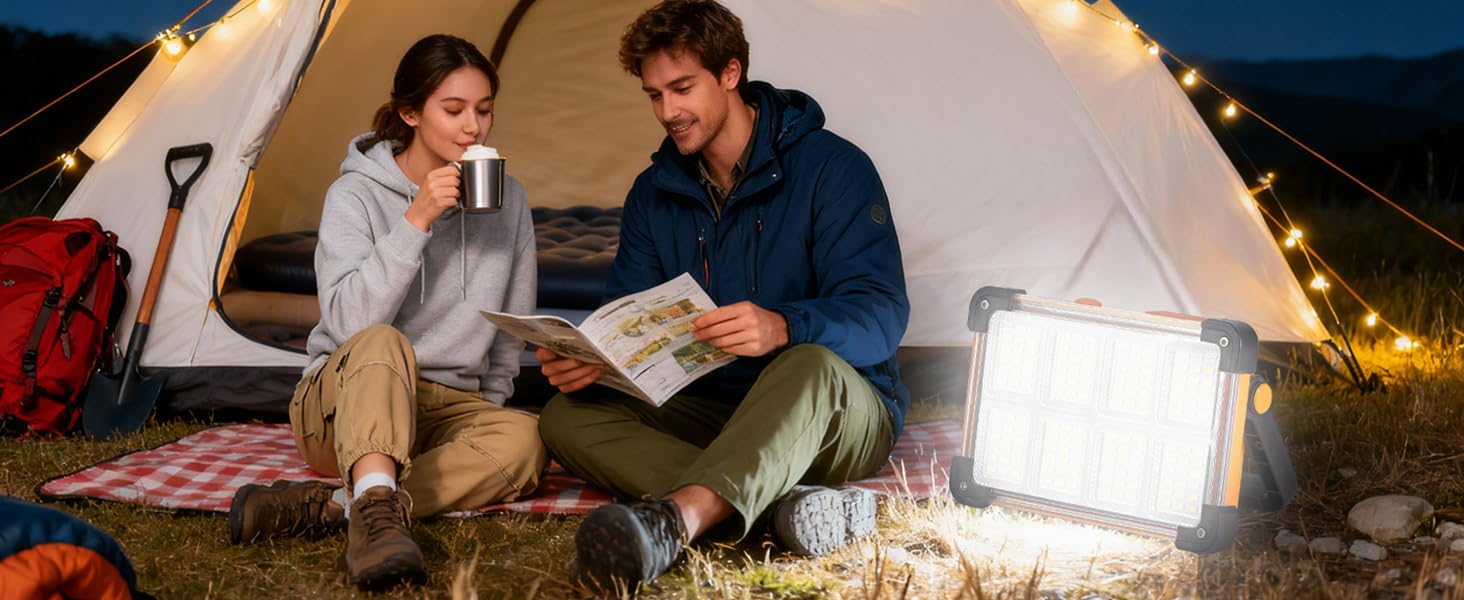 Camper reading book inside tent at night with portable LED work light as camping lantern