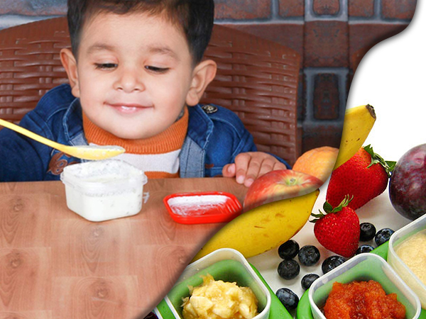 Colorful lunch or snack spread featuring fresh fruits, strawberries, dipping sauces, and various healthy food items arranged in small containers.