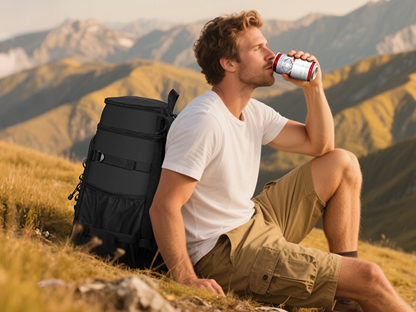 A man on a cliff, opening his ice pack backpack and drinking cold beer
