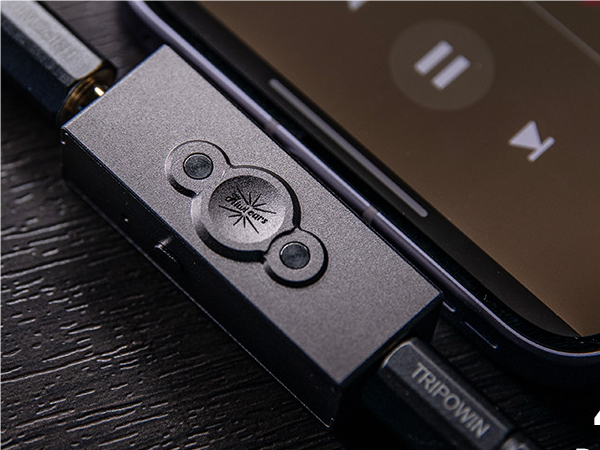 Close-up of device control buttons featuring circular pattern design on dark metallic surface.
