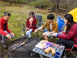 Family cooking together on a campground fire pit grill