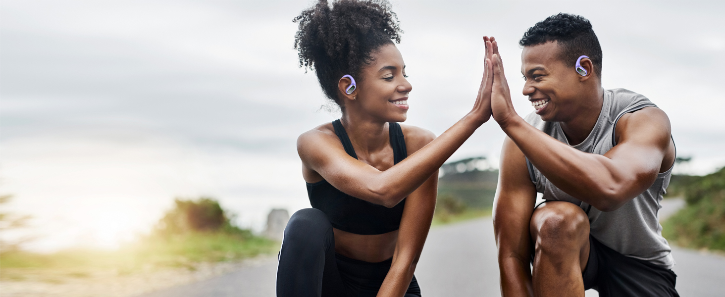 Two people in athletic wear giving each other a high-five outdoors during what appears to be a workout session at sunset.