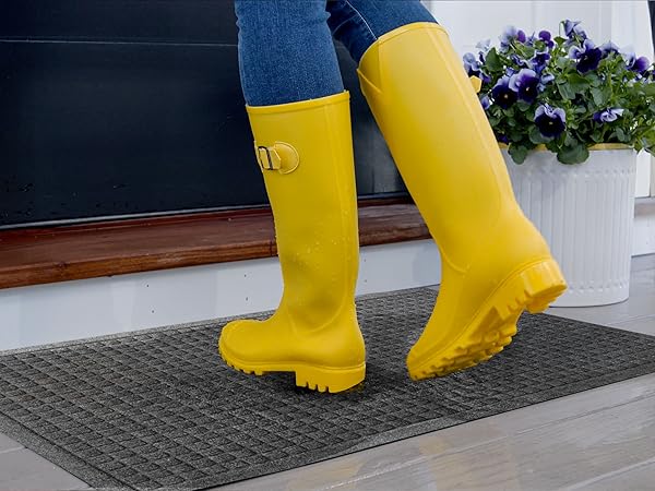 yellow rain boots wiping across doormat at outdoor entry door
