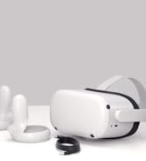 White virtual reality headset with controllers and cable on a light gray background.