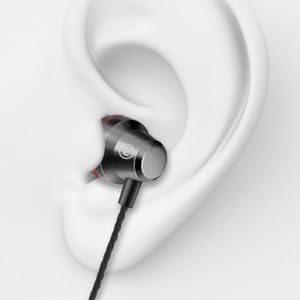 Close-up of a black in-ear headphone earbud inserted into an ear. The earbud has a metallic accent and attached cable.