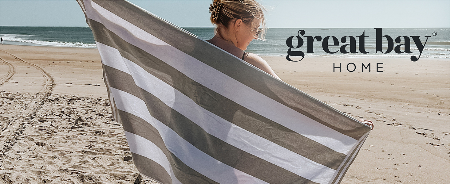 Woman holding out a cabana-striped beach towel by Great Bay Home