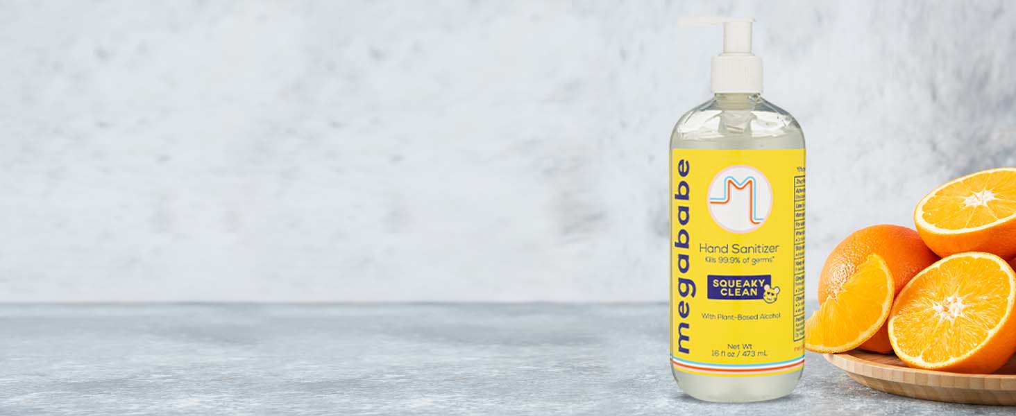 Hand Sanitizer on grey background next to oranges.