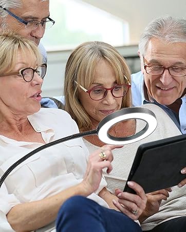 A handheld magnifying device with LED lighting being used to view content on a digital device or document.