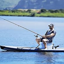 Inflatable fishing kayak in blue water with mounted rod holder and seat, being used for recreational fishing on a calm lake.