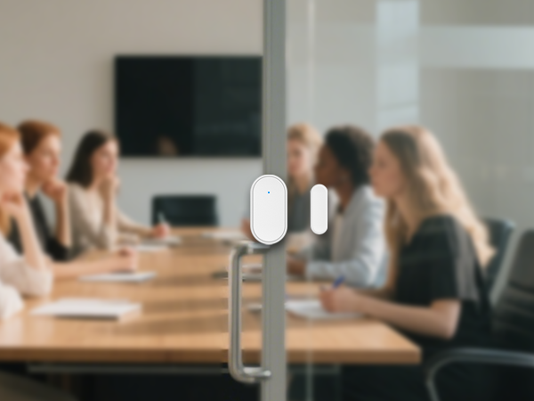 People sitting at conference tables in modern office environment, showing meeting or collaborative workspace setting.